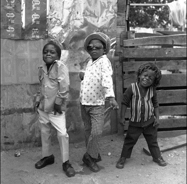 22. Jamaika sokaklarında kameraya poz veren 3 çocuk