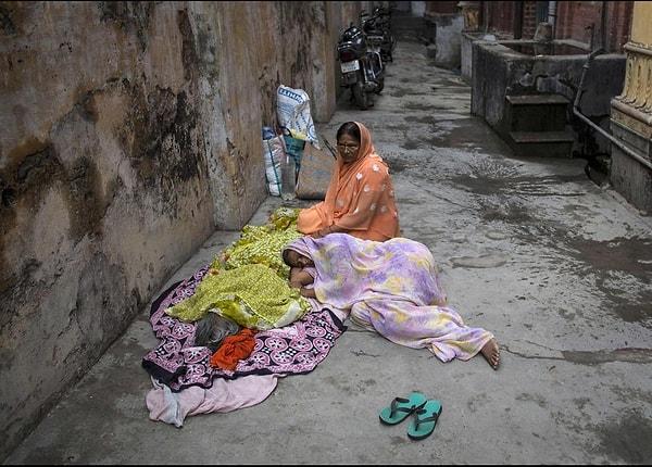 8. 49 yaşındaki Devki Rai, yerde cansız yatan annesinin bedeninin yanında oturuyor. Rai, üzgün ama annesi son nefesini Varanasi'de verdiği için huzurlu.