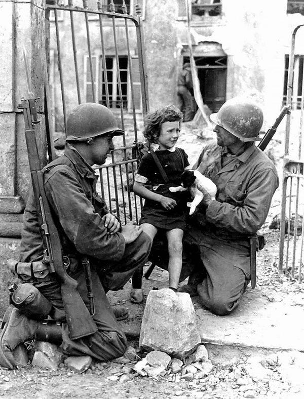 2. Yine 2. Dünya Savaşı sırasında iki Amerikan askeri yavru köpeği ile birlikte korkmuş küçük kızı rahatlatmaya çalışıyor.