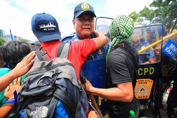 29. Göstericiler tarafından darp edilen polis müdürü diğer göstericiler tarafından teselli ediliyor.(Quezon, Filipinler)