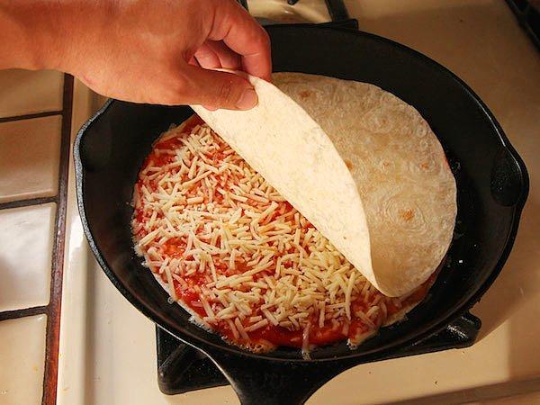 1. Kısık ateşte ısıttığımız yağlı tavaya ilk tortilla hamurunu koyuyoruz, üzerine pizza sosu ve peynirimizi koyduktan sonra ikinci kat hamuru üzerine koyup kapatıyoruz.
