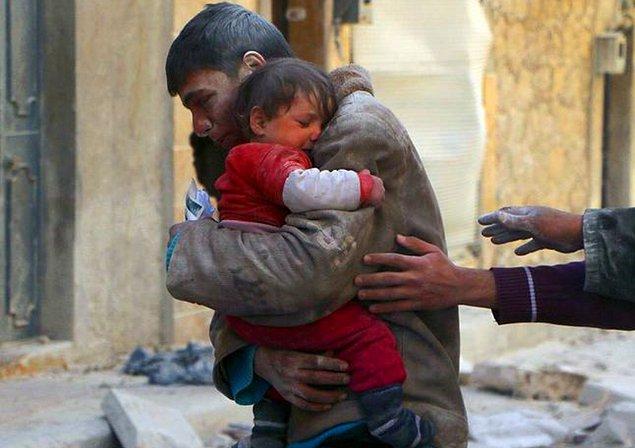 8.Suriyeli bir delikanlı, bombalanan evlerinden kız kardeşini sağ çıkardıktan sonra ona sarılırken.
