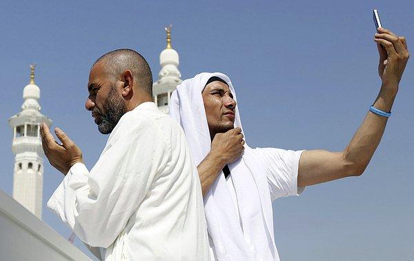 22. Mekke'de hac ibadetini gerçekleştiren hacılardan birisi dua ederken, diğeri selfie çekiyor.