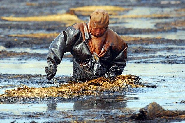 9. Dalian'daki bir işçi, sudaki pisliği çıkarmaya çalışıren.