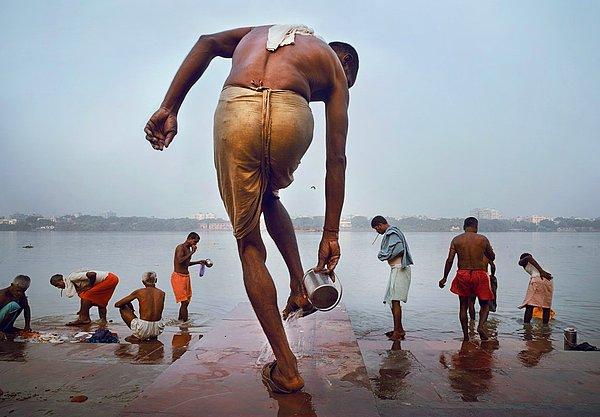 6. Kalküta'daki Hooghly Nehri'nde kutsal banyosunu yapmadan hemen evvel ayaklarını yıkayan bir adam.