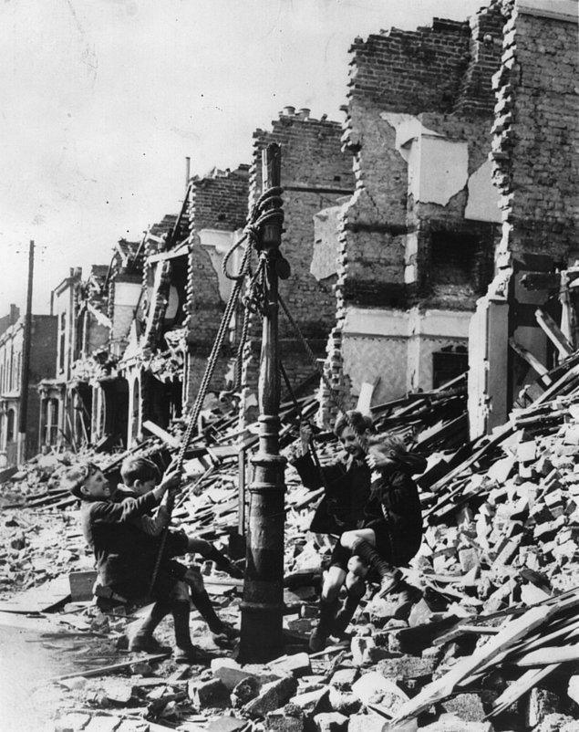 10. 1940 yıllarında hava bombardımanından arta kalan kırık dökük yerlerde bir lambada sallanan Londralı çocuklar.
