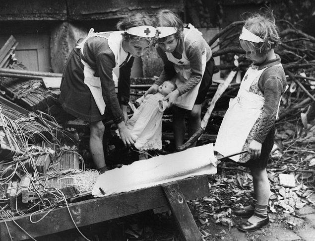 16. Hava savunması amirlerinin küçük kızları, Londra'nın güney doğusunda oyuncak bebekleriyle ilk yardım alıştırması yaparken, İkinci Dünya Savaşı, 6 Ekim 1940.