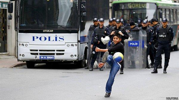 Polislerin Taksim'e girişi engellediği bir yolda top oynayan bir çocuk