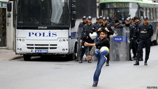 Polislerin Taksim'e girişi engellediği bir yolda top oynayan bir çocuk