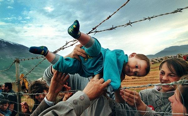 4. Kosova Savaşı'nda ülkeyi terk eden ve yeniden bir araya gelen ailenin 2 yaşındaki üyesi Arap Kampının dikenli telleri üzerinden geçirilirken:
