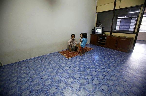 10. Malezya'nın başkenti Kuala Lumpur'da, Myanmarlı mülteci bir aile henüz boş olan evlerinde televizyon seyrederlerken.