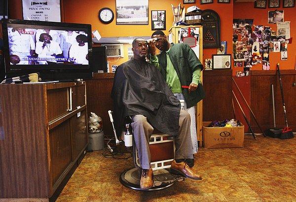 16. New Jersey, ABD'de saçlarını kestiren bir adam ve arkasında açık duran televizyon.