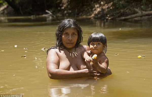14. Bir kadın çocuğuyla ormanın ortasındaki nehirde yıkanırken. Ormanlar tarım ve yangınlar nedeniyle yavaş yavaş yok oluyor.