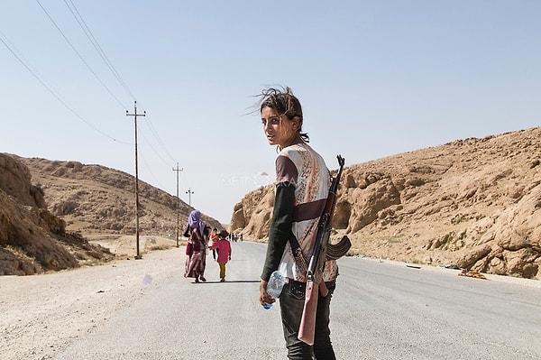26. Ailesini IŞİD'den korumak için tüfek taşıyan Yezidi kız çocuğu.