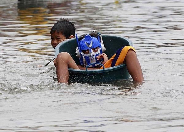 19. Linfa Tayfunu'nun sebep olduğu sel sırasında leğenin içindeki arkadaşını kurtarmaya uğraşan bir çocuk. Malabon, Manila. 6 Temmuz 2015.