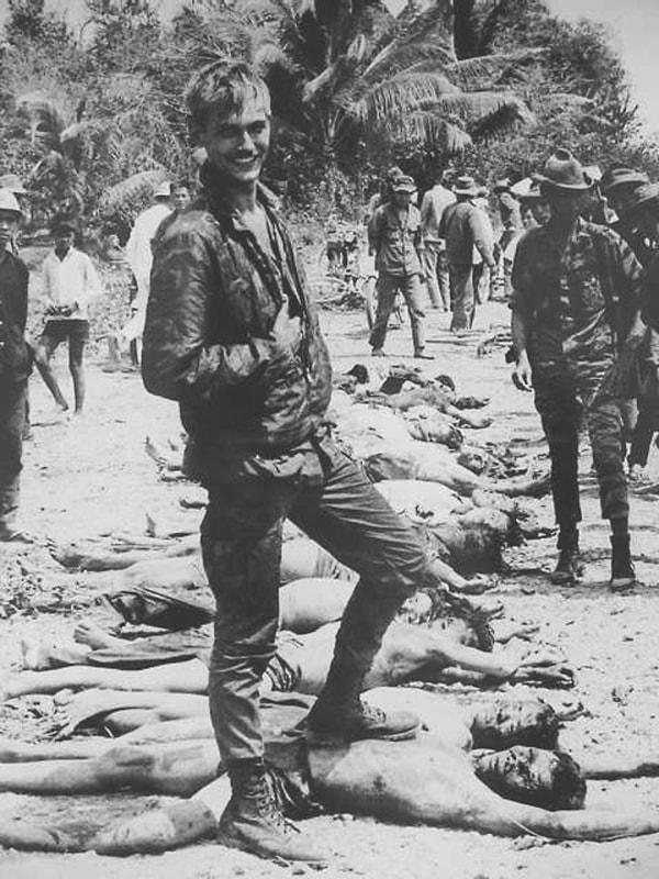 26. Bir Amerikan askeri, Güney Vietnam'da çatışıp öldürdükten sonra soydukları Vietkong gerilla savaşçıları ile poz verirken, 1968.