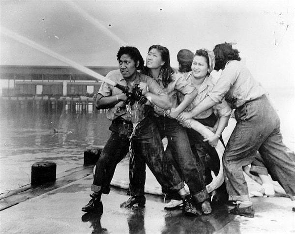 19. Japonların saldırısı sonrası ABD deniz üssü Pearl Harbor'da kadın itfaiyeciler tazyikli hortumu tutmaya çalışırken, 1941.