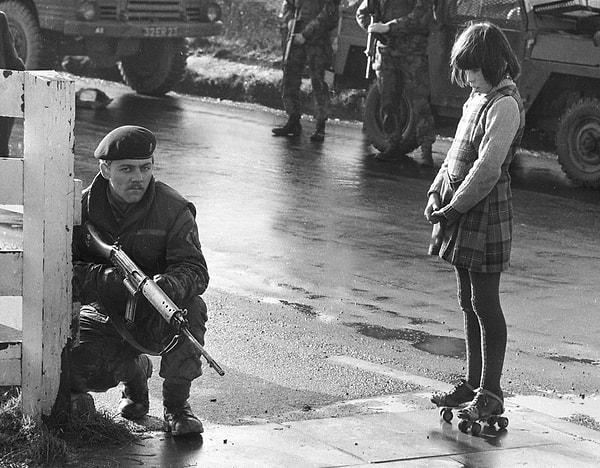 27. Kargaşa zamanlarında paten giymiş İrlandalı bir kız Britanya askerine bakarken, Kuzey İrlanda, 1970 sıraları.