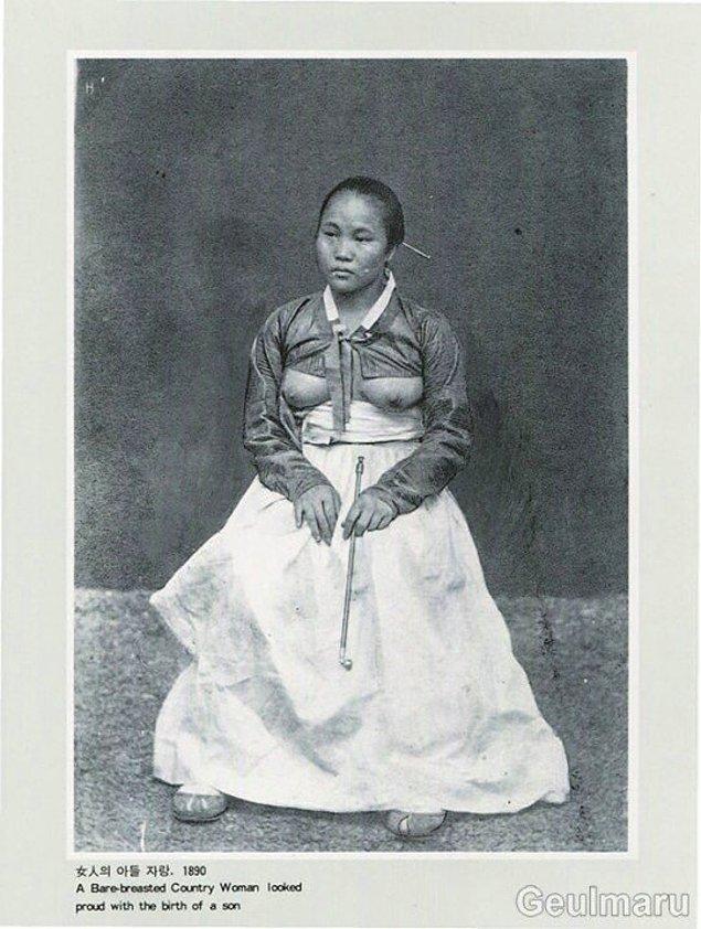18. Kore'de geçmişte yaygın bir gelenek olan, bir erkek çocuğu doğurduğunun göstergesi olarak göğüslerini açıkta bırakmış Koreli bir köylü kadın, 1890.