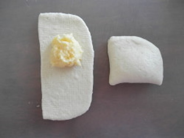 В большую часть раскатанного теста выложите по ложке крема и хорошенько зажмите края.