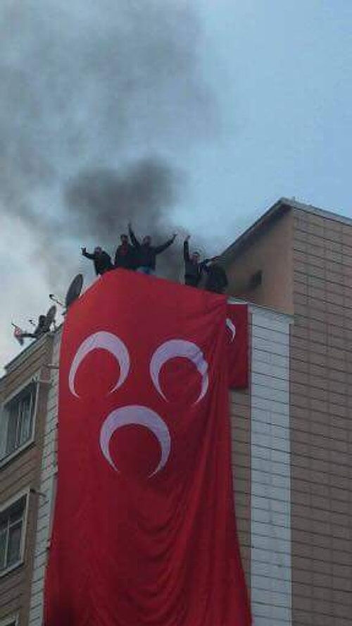 Binanın camları taşlanırken çatıya çıkan grup bayrak astı