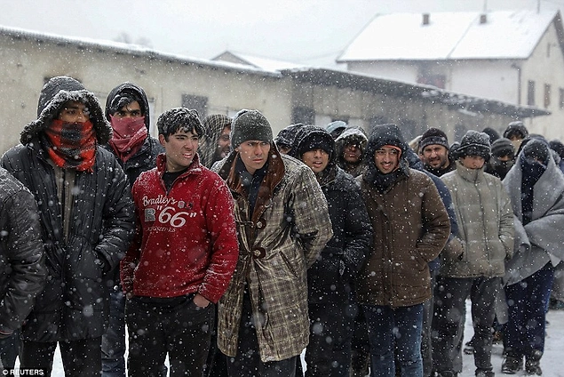 Diğer göçmenler de soğuktan korunabilmek için kat kat giyinmiş, sırada bekliyorlar.