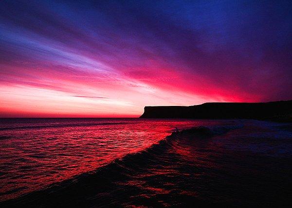 21. İngiltere'nin Saltburn-by-the-Sea kentinde Huntcliff uçurumu ve ardından doğan güneş ile kırmızıya boyanmış gökyüzü.