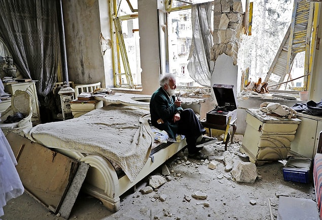 8. Mohammed Mohiedin Anis, 70, smokes a pipe and listens to music on his vinyl record player in his destroyed bedroom in Aleppo’s formerly rebel-held al-Shaar neighborhood.