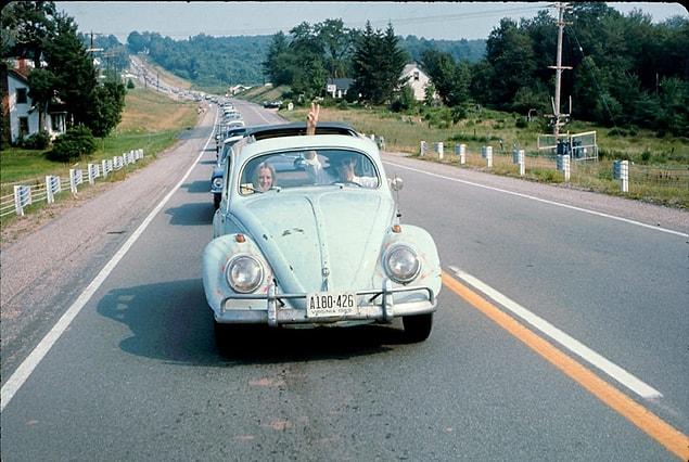 16. A man driving a Volkswagen Beetle makes his way to the Woodstock Music and Arts Fair as he flashes a peace sign through the sunroof in 1969.