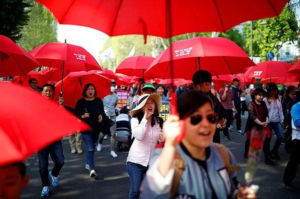 11. Sendikalı işçiler kırmızı şemsiyeleriyle yürüyor
