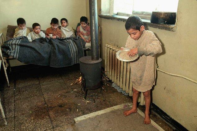 3. Arnavutluk Akıl Hastanesi'nde kendisine verilen yemeği elleriyle yiyen çocuk ve arkasındaki küçük yatakta oturan diğer çocuklar, yıl 1992.