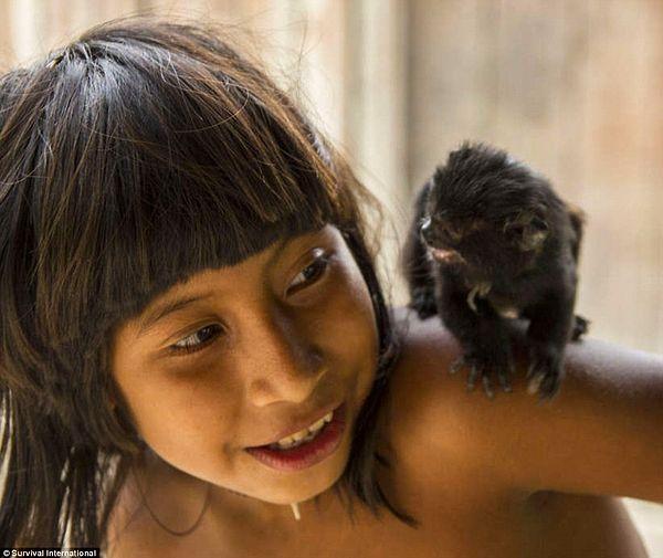 A young boy with one of his family's adopted pets, which even once returned to the wild are still considered a member of the tribe.