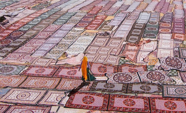 10. Hindistan'da kurumaya bırakılmış örtülerin üzerinden yürüyüp giden bir kadın.