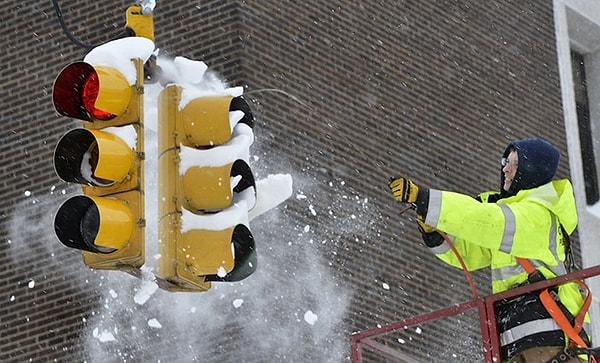 26. Erie şehri trafik teknik ekibinde çalışan adam basınçlı hava ile trafik lambasını engelleyen karları temizlemeye çalışıyor.