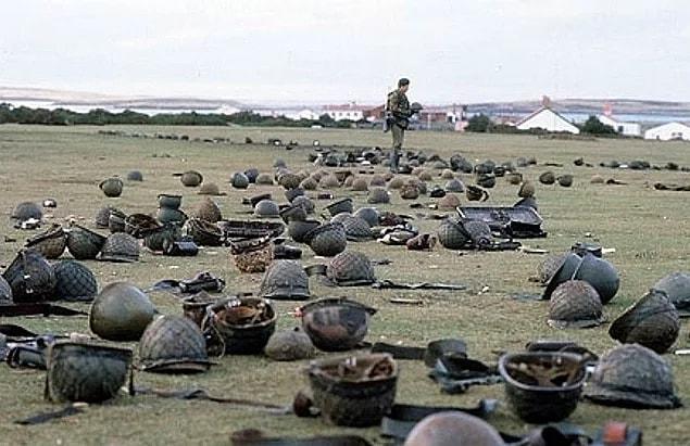 20. British soldier checking helmets of 	Argentinean soldiers after one of the battles in Falkland Islands, 1982