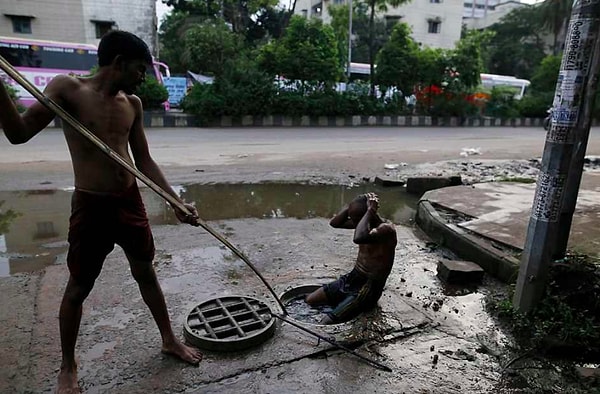 Başkent Dhaka'da her yıl onlarca işçi, kanalizasyonları koruyucu ekipman olmadan, bir çubuk yardımıyla temizlerken can veriyor.