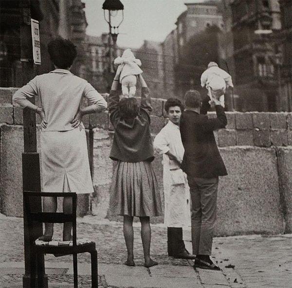 23. Doğu Berlin'deki ebeveynlerine duvarın üstünden torunlarını gösteren Batı Berlinli çift.