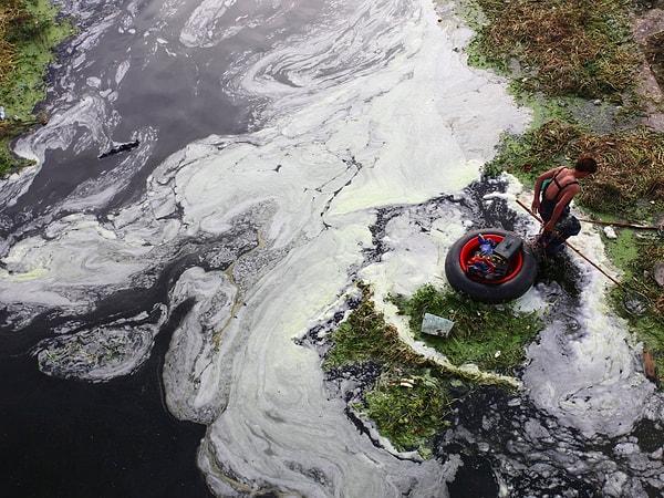 26. Bir adam Xi'an'da bir nehir ağzında elektrikli sırıklarla balık avlamaya çalışıyor. Yetersiz kanalizasyon çalışmaları yüzünden şehrin atıklarının %60'ı Zao Nehri'ne gidiyor
