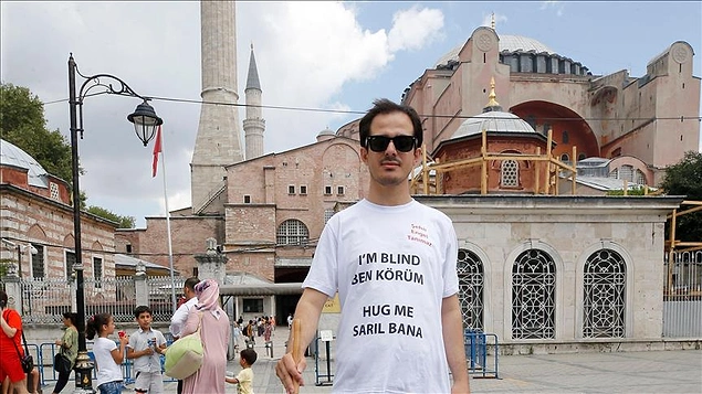 Üzerinde Türkçe ve İngilizce 'sarıl bana' yazılı tişörtü ile turistlerin ilgisini çeken Polat, 'Görme engelli biri size aşık olsa ne düşünürsünüz?' sorusuyla da halkın nabzını tuttu.