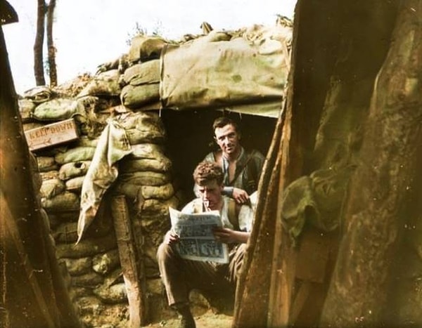 12. Ирландские солдаты читают газету. Лето 1916 года, северо-западная Бельгия. Обратите внимание на табличку Keep down («Пригнись!») на стене траншеи