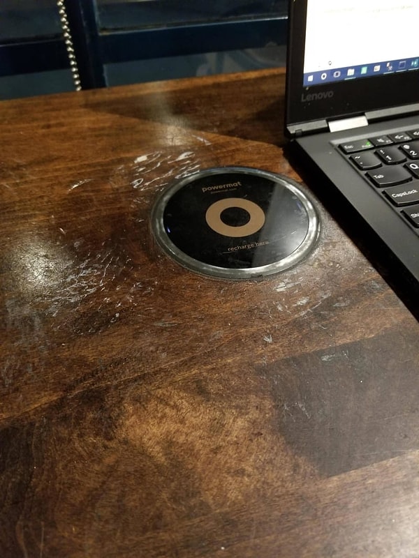 14. Инновации и модернизация. Беспроводное зарядное устройство, вмонтированное в стол в кофейне.