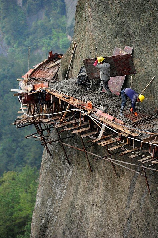 1. Turistleri çekebilmek için dağın kenarında yeni bir yol yapmaya çalışan Çinli işçiler.