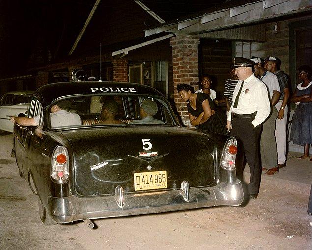 13. Greenville'de üstsüz bir adam ahlak dışı davrandığı gerekçesiyle tutuklanırken komşuları izliyor, 1956.