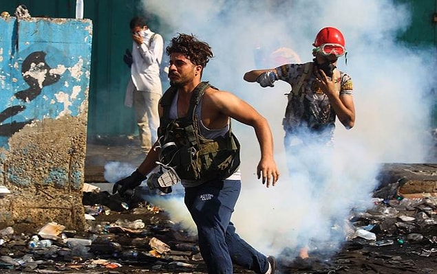 Protestocular, polis güçlerinin fırlattığı göz yaşartıcı gazlardan kaçıyor.