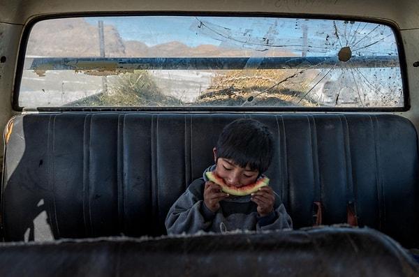 64. Ailesi Bolivya'daki tuz tarlalarında çalışırken küçük Angelo arabada karpuz yiyor. Cédric Gerbehaye imzalı bir fotoğraf.