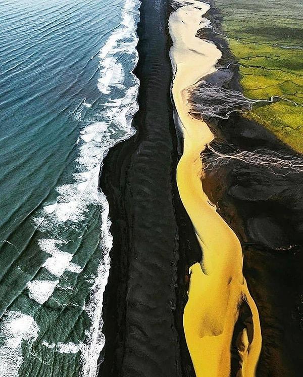 17. İzlanda'daki yeşil tarlalar, sarı nehir, siyah kumsal ve okyanusun ortaya çıkardığı görüntü...