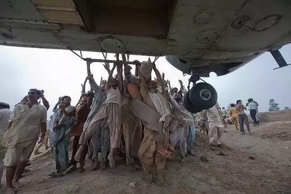 37. Pakistan'da sel mağdurları yemek yardımı yapan helikoptere tutunarak bölgeden kaçmaya çalışıyorlar, Ağustos 2010.