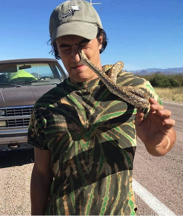 Yol kenarında bulduğu bir yılanla fotoğraf çekmeye hevesli bir adam: