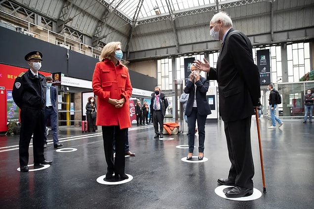 Paris'teki 'Gare de l'Est Tren İstasyonu'nda sosyal mesafe belirteçleri üzerinde duran bürokratlar.