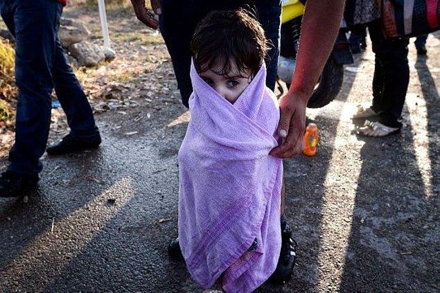 15. Suriyeli baba, Yunanistan'a deniz yoluyla geçişlerinin ardından çocuğunu havluya sarıyor.